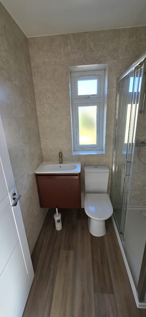 Ensuite bathroom refurbishment with beige tiles, fluted vanity and wood-effect flooring by Ikveles Construction