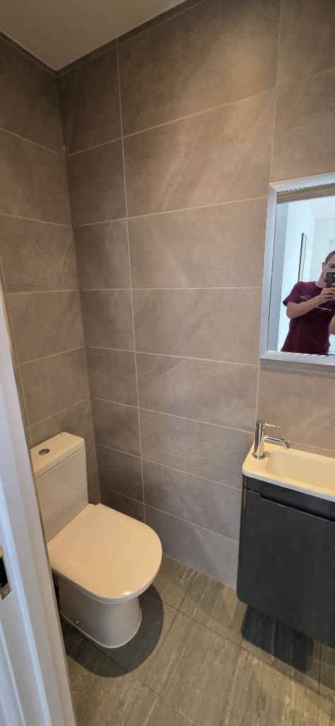 Compact cloakroom refurbishment with grey stone-effect tiles and modern vanity by Ikveles Construction