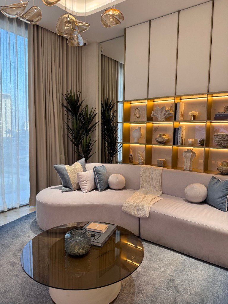 Modern living room interior finish with curved sofa and lit shelving by Ikveles Construction