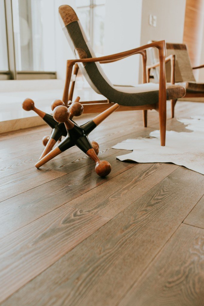 Dark wide-plank wood flooring in a modern living room by Ikveles Construction