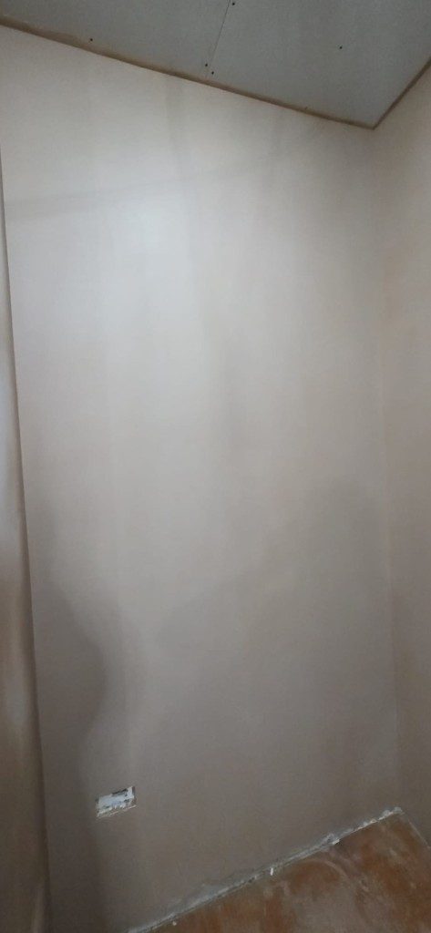 Freshly plastered wall section with socket cutout by Ikveles Construction
