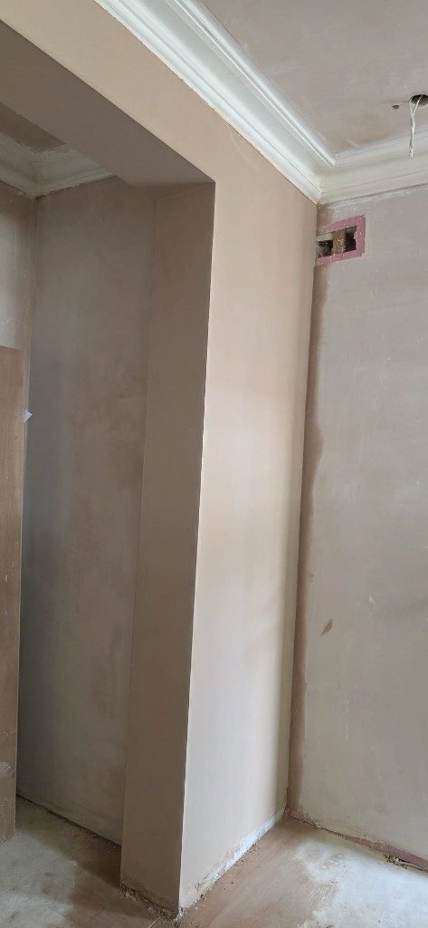 Fresh plaster on walls and pillar with white coving by Ikveles Construction