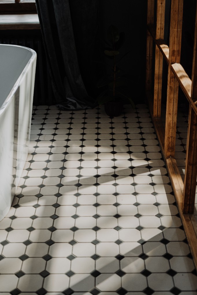 Bathroom floor tile installation with octagonal cream tiles and black diamond accents by Ikveles Construction