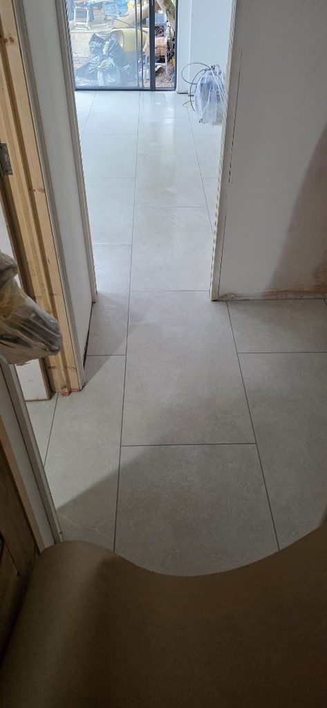 Precision grey stone-effect floor tiling through a renovation hallway by Ikveles Construction